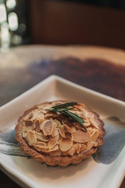 Kafedeki ahşap masada servis edilen küçük turta badem dilimi..