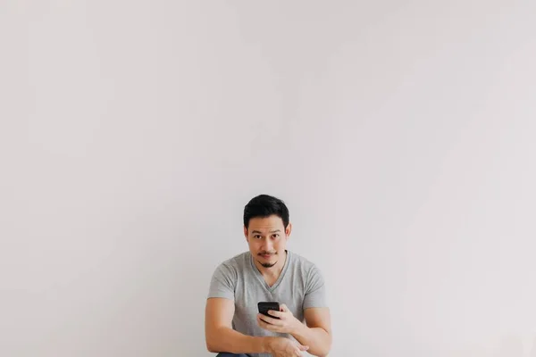 Minimal portrait of Asian man using smartphone at the bottom with empty space.