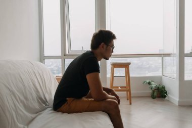 Yalnız Asyalı adam evinde çaresizce kanepede yatıyor..