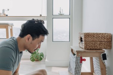 Asyalı adam odasında küçük şeker planörüyle oynuyor..