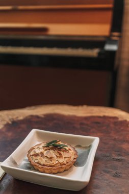 Kafedeki ahşap masada servis edilen küçük turta badem dilimi..