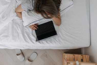 Asyalı kadın sabahları tablet bilgisayarın üzerinde uyur. Erken çevrimiçi çalışma.