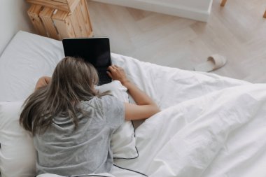 Asyalı kadın sabahları tablet bilgisayarın üzerinde uyur. Erken çevrimiçi çalışma.