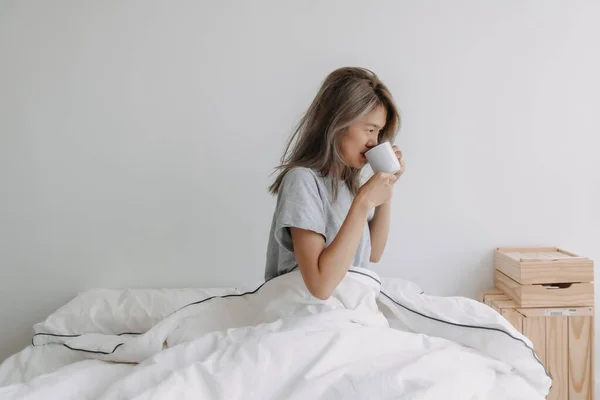 亚洲女人早上一醒来就在床上喝咖啡 — 图库照片