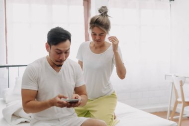 Komik Asyalı çift. Akıllı telefondan konuşan, dikizci bir eş..