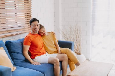 Sevgili Asyalı çift aşığı sıcak evdeki kanepede birlikte oturuyorlar..