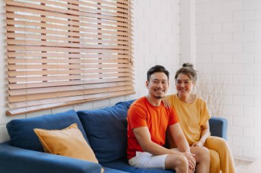 Sevgili Asyalı çift aşığı sıcak evdeki kanepede birlikte oturuyorlar..