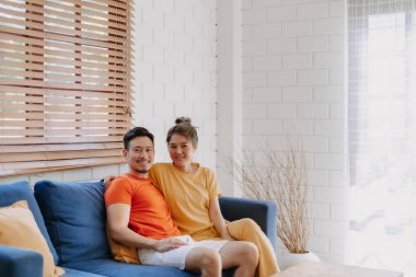 Sevgili Asyalı çift aşığı sıcak evdeki kanepede birlikte oturuyorlar..