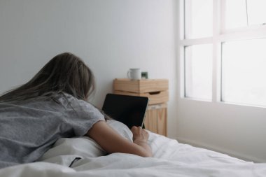 Asyalı kadın sabahları tablet bilgisayarın üzerinde uyur. Erken çevrimiçi çalışma.