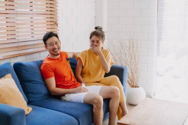 Sevgili Asyalı çift aşığı sıcak evdeki kanepede birlikte oturuyorlar..