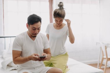 Komik Asyalı çift. Akıllı telefondan konuşan, dikizci bir eş..