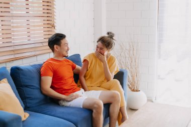 Sevgili Asyalı çift aşığı sıcak evdeki kanepede birlikte oturuyorlar..