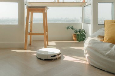 Apartmanın ahşap zemininde modern robot elektrikli süpürge..