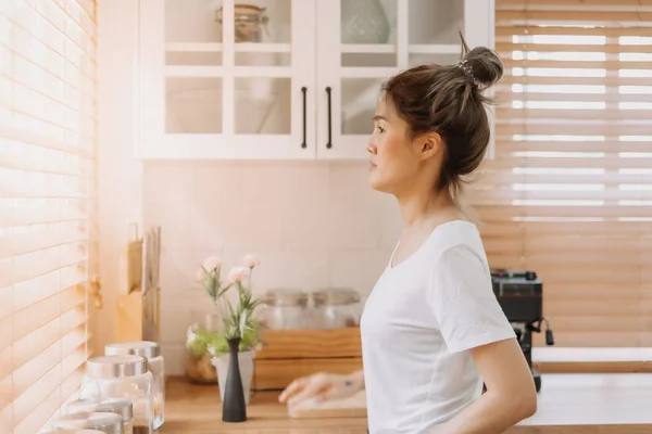 Wanita Asia Melihat Keluar Jendela Dari Dapur Putih Yang Hangat — Stok Foto