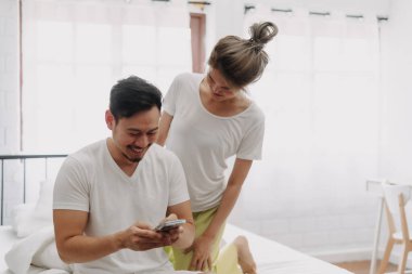 Komik Asyalı çift. Akıllı telefondan konuşan, dikizci bir eş..