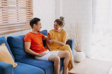 Sevgili Asyalı çift aşığı sıcak evdeki kanepede birlikte oturuyorlar..