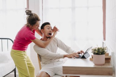 Asyalı bir eş, çalışmayı bırakmak için kocasını masadan çekiyor. Komik çift kavgası.