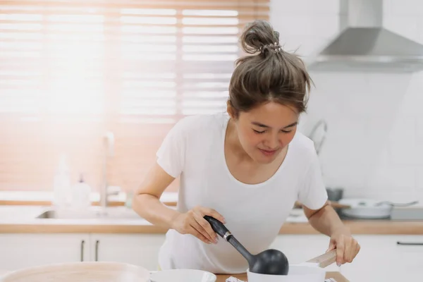 Happy asian woman cooking and smell the soup, preparing meal for husband.