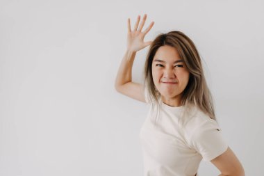 Beyaz tişörtlü Asyalı bir kadının kızgın yüzü beyaza bürünmüş..