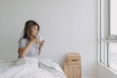 Asyalı kadın sabah uyanır uyanmaz kahve içiyor..