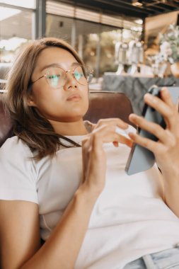 Kafede akıllı telefon kullanan sıkıcı Asyalı kadın..