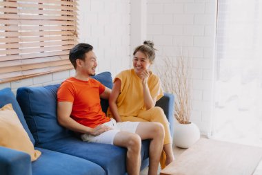 Sevgili Asyalı çift aşığı sıcak evdeki kanepede birlikte oturuyorlar..