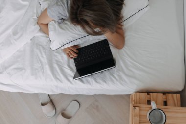 Asyalı kadın sabahları tablet bilgisayarın üzerinde uyur. Erken çevrimiçi çalışma.