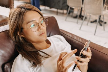 Kafede akıllı telefon kullanan sıkıcı Asyalı kadın..