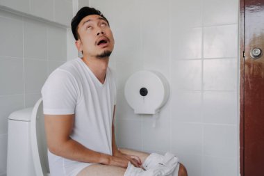 Funny happy face of asian man able to poop after suffer from constipation. clipart