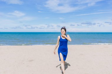 Asyalı bir kadın güneşli sahilde yürüyor. Güneşin teninde yandığını hissediyor..