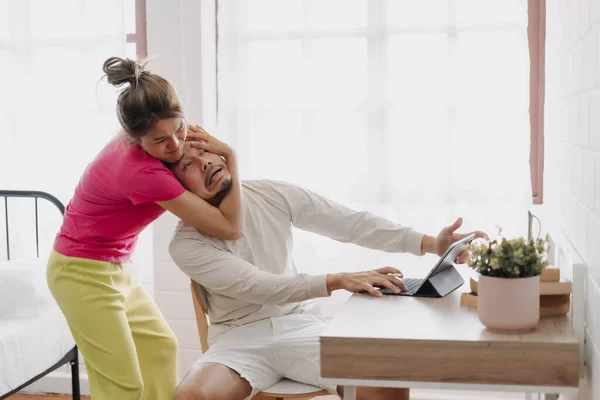 stock image Asian wife pulling husband out of the desk to stop working. Funny couple fight.