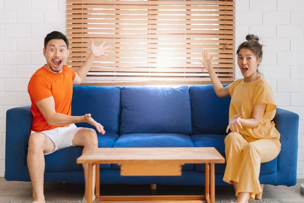 Wow and surprised face asian couple lover sit on sofa showing at empty space.