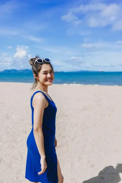 stock image Vertical portrait of happy asian woman in. blue dress walking on the beach.