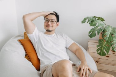 Mutlu Asyalı adam, bir gün oturma odasındaki armut çuvalında rahatla..