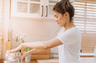 Asyalı kadın ekipman malzemelerini yeniden düzenler ve mutfağı temizler..