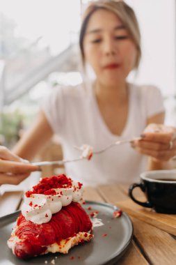 Pasta, kafede Asyalı bir kadın tarafından yeniyor. Pastaya odaklan..