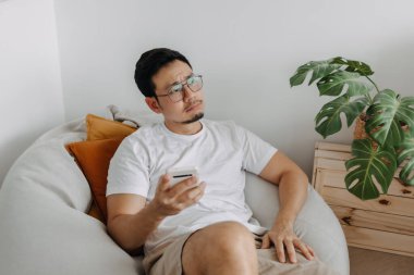 Asyalı adamın komik suratı. Akıllı telefondan kendini kötü ve kötü hissediyor..