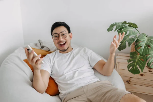 Happy funny face asian man surprised with the advertisement in the smartphone.