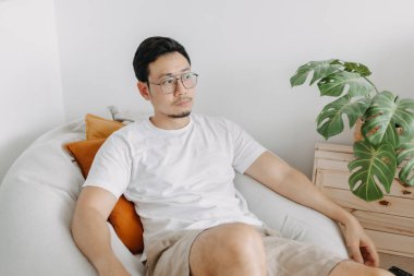 Mutlu Asyalı adam, bir gün oturma odasındaki armut çuvalında rahatla..