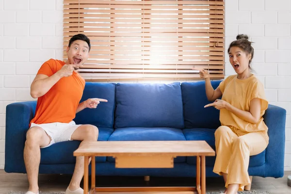 Wow and surprised face asian couple lover sit on sofa showing at empty space.