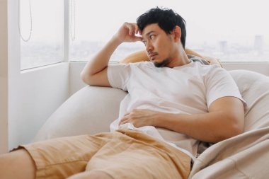 Asyalı adam hafta sonları evdeki kanepede dinleniyor ve dinleniyor..