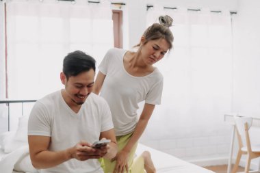 Komik Asyalı çift. Akıllı telefondan konuşan, dikizci bir eş..