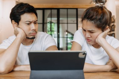 Kafedeki Asyalı çift aşığı, tablet bilgisayardaki başvuru ile karıştırıyor..