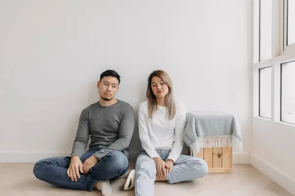 Boring and tired faces of asian lover sit on the floor of empty room.