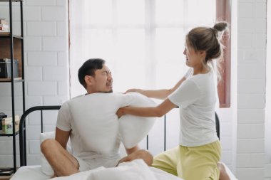 Asyalı karı koca yastık savaşı yapıyor. Komik ve yatakta gülüyorlar..