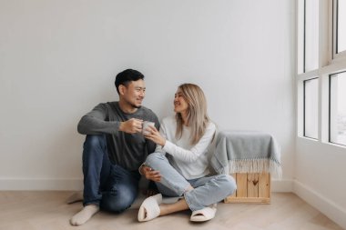 Mutlu Asyalı çift desteği sarılma ve kahve ile yere otur..