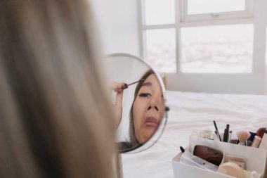 Aynada makyaj yapan Asyalı kadın. Alet edevat ve teçhizatla..