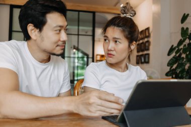 Erkek, kafede bilgisayar tabletli kadını öğretiyor ve gösteriyor, Asyalı çift..