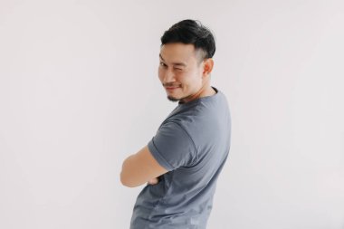 Mutlu Asyalı adam mavi tişört giyer ve kot pantolon giyer kameraya göz kırpar ve gülümser..