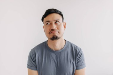 Mavi tişörtlü Asyalı adamın hayal kırıklığına uğramış ve sıkılmış yüzü beyaz duvarda izole bir şekilde duruyor..